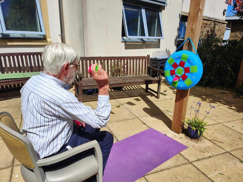 older man throwing a ball in a garden