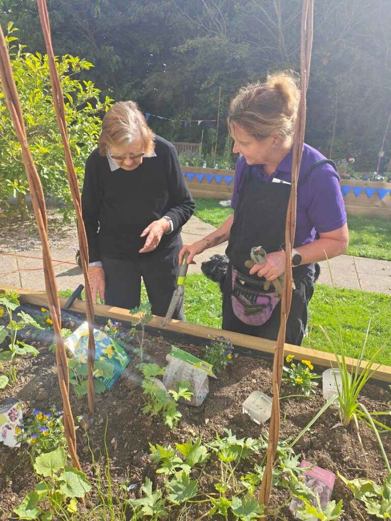 resident and carer gardening together