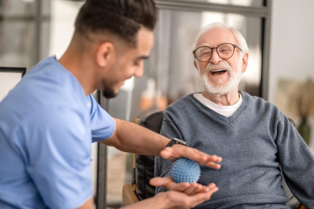 carer and resident using sensory ball while smiling