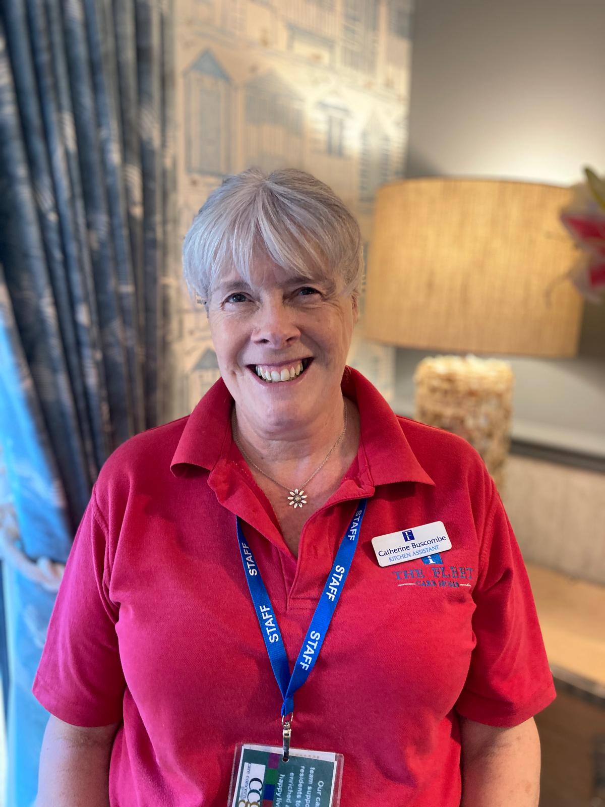 lady in a pink shirt with short grey hair smiling